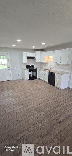 A kitchen with white cabinets and a wooden floor.