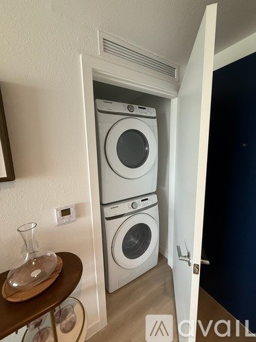 A small room with a washing machine and a table with a vase on it.