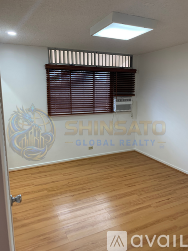 A room with wooden flooring and a window with blinds.