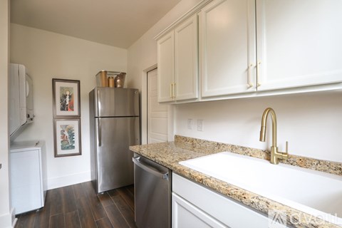 A kitchen with a stainless steel refrigerator and a granite countertop.