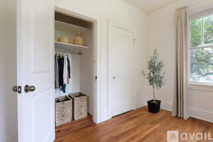 A room with a white door, a plant, and a coat hanging up.
