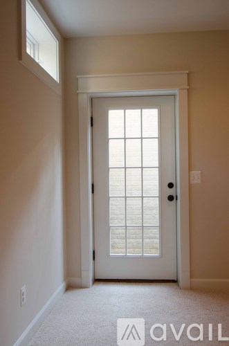 A white door with a window above it in a room with beige walls.