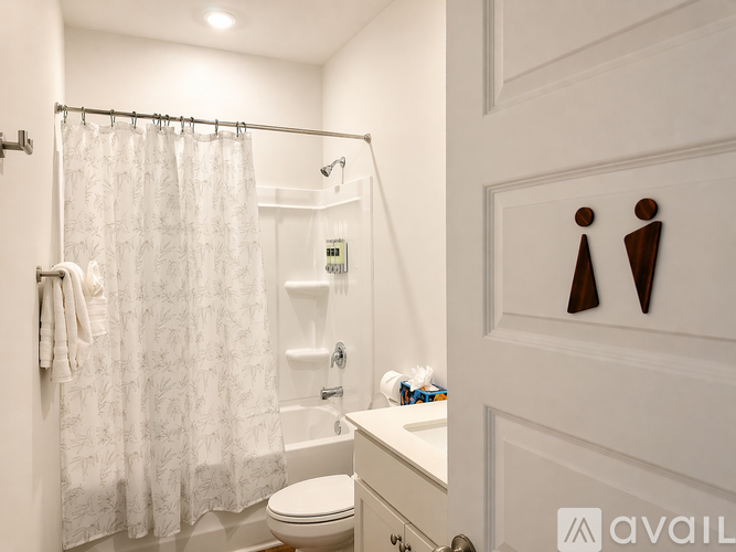 A white bathroom with a toilet, sink, and shower curtain.