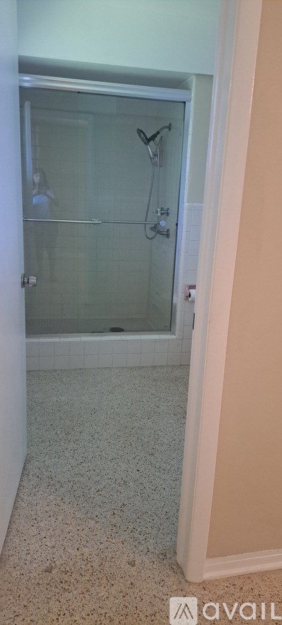 A bathroom with a glass shower door and a tiled floor.