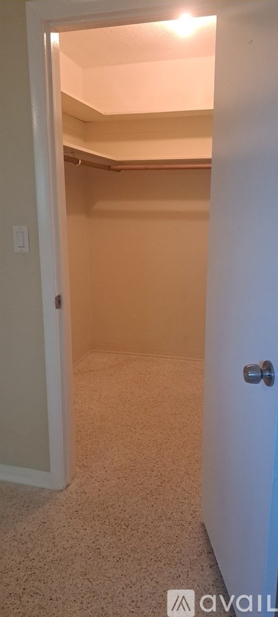 A small, empty room with a carpeted floor and a door on the right.