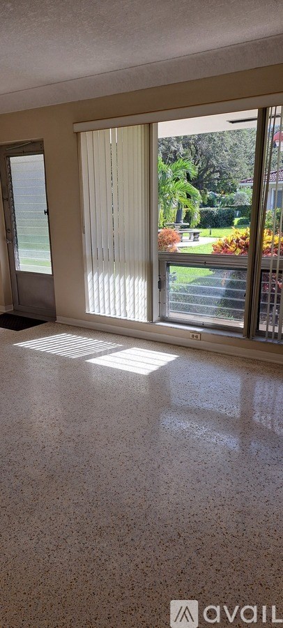 A room with a tiled floor and a view of a garden through the window.