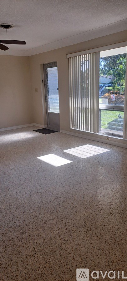 A room with a ceiling fan and a door leading outside.