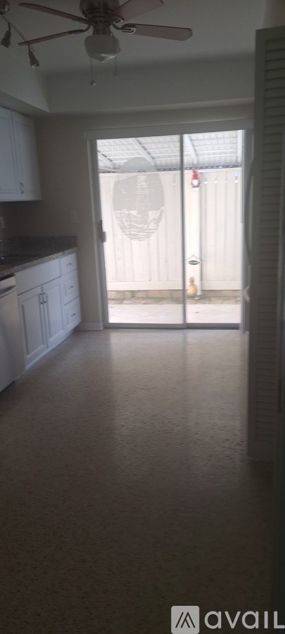 A room with a ceiling fan and a door leading outside.