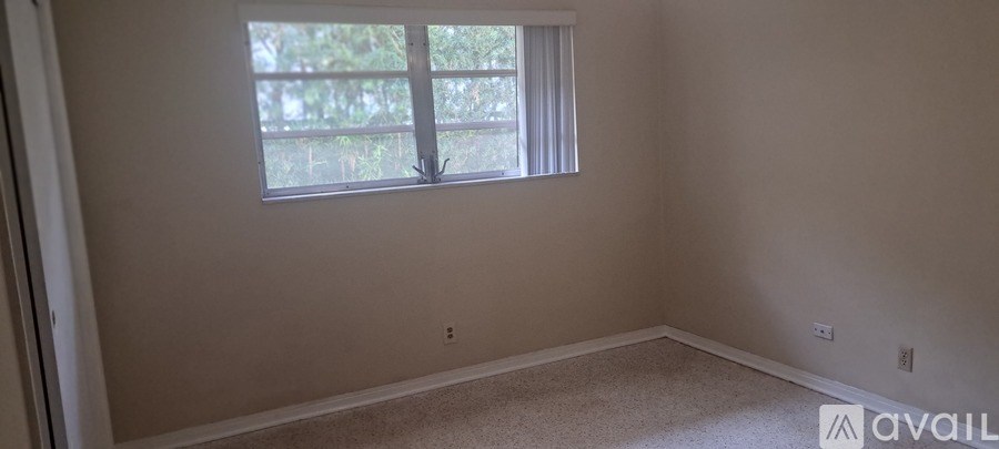 A room with a window and a carpeted floor.