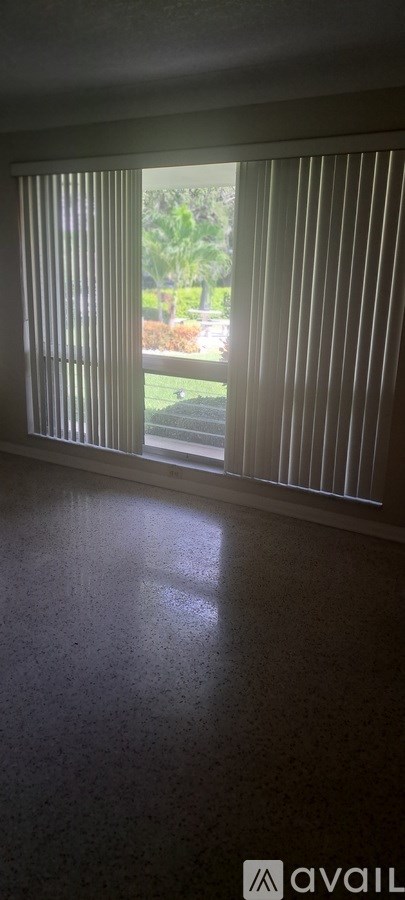 A room with a ceiling fan and a window with blinds.