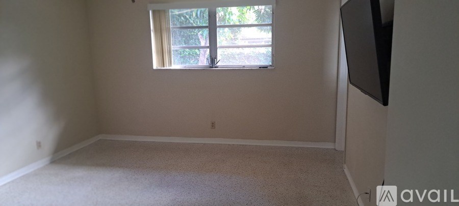 A room with a window and a flat screen TV mounted on the wall.