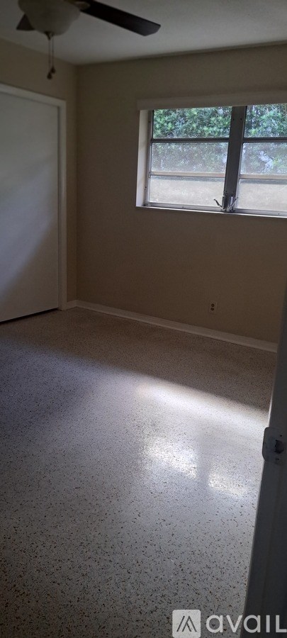 A room with a ceiling fan and a window.