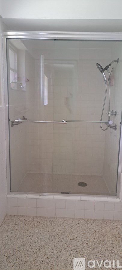 A shower area with a glass door and a drain in the middle of the floor.