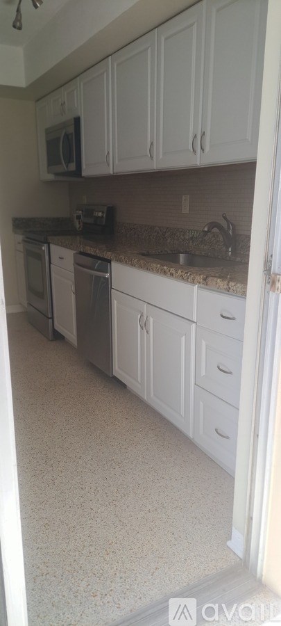 A kitchen with white cabinets and a granite countertop.