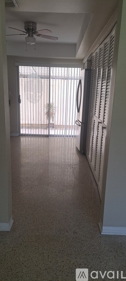 A room with a ceiling fan and a window with blinds.