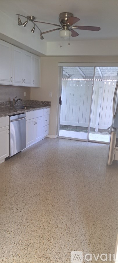 A kitchen with white cabinets and a fan.