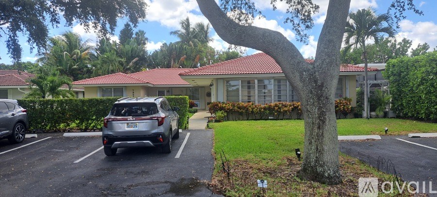 A silver car is parked in a parking lot in front of a house.