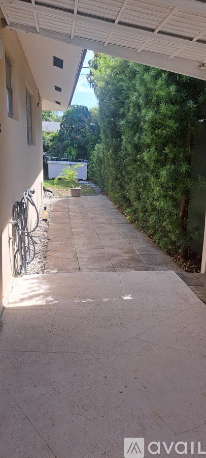 A white covered walkway leads to a lush green area.