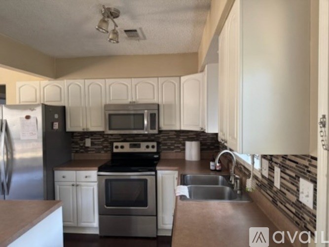 A kitchen with a refrigerator, oven, and sink.