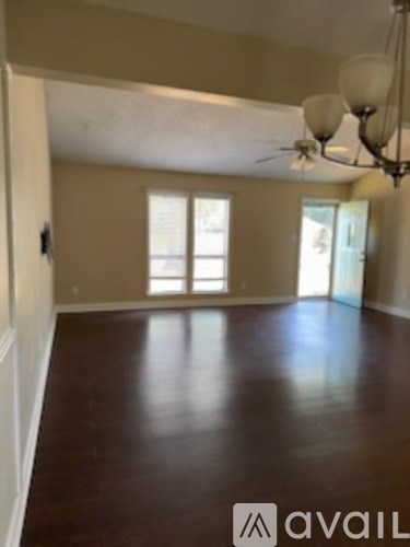 A room with brown flooring and a ceiling fan.