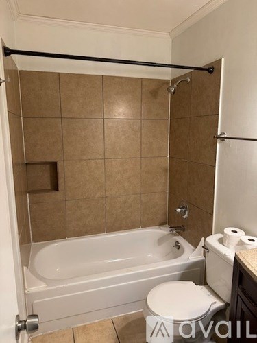 A bathroom with a toilet, tub, and towels.
