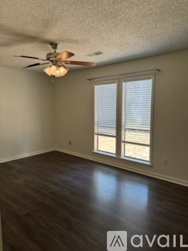 A room with a ceiling fan and a window with blinds.