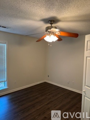 A room with a ceiling fan and wooden flooring.