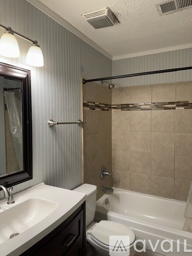 A bathroom with a sink, mirror, and bathtub.