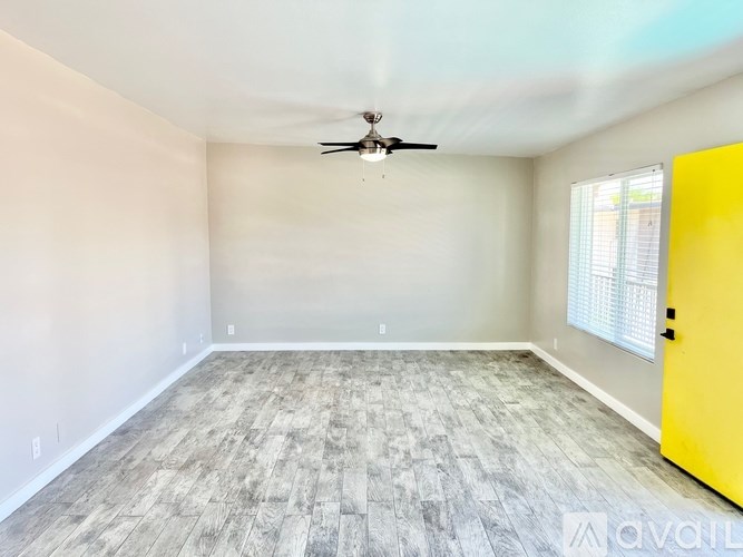 A room with a ceiling fan and a yellow door.
