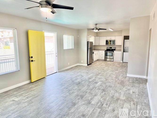 A spacious kitchen with a yellow door and a ceiling fan.