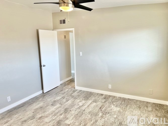 A room with a ceiling fan and a door leading to another room.
