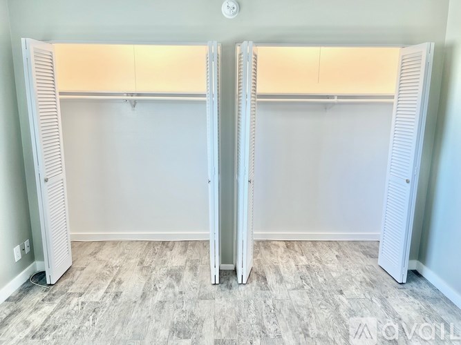 Two white closet doors with shelves above them.