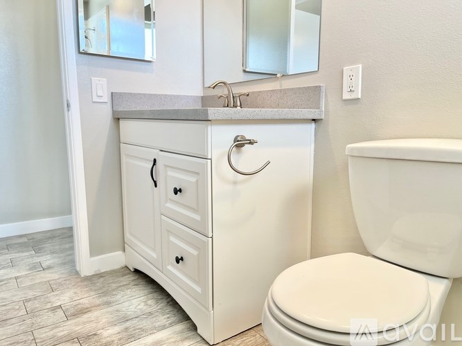 A white bathroom vanity with a sink and a toilet.