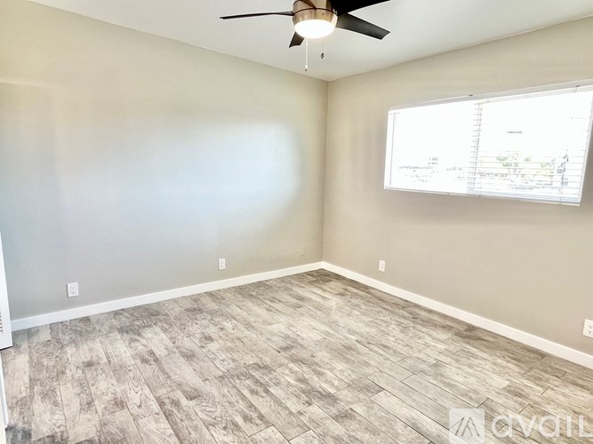 A room with a ceiling fan and a window with blinds.