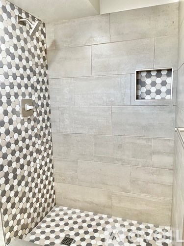 A shower with a tiled floor and walls.