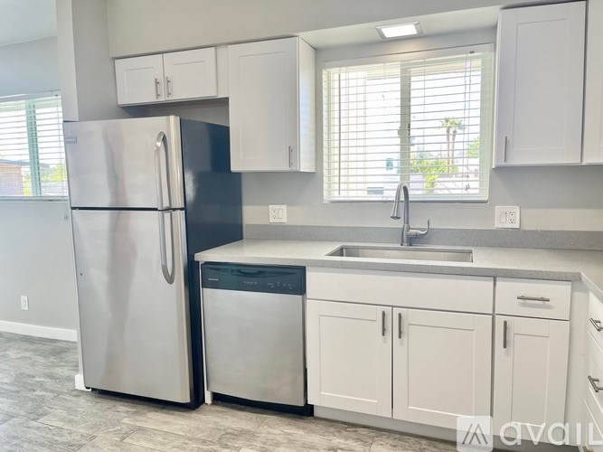 A kitchen with a stainless steel refrigerator and white cabinets.