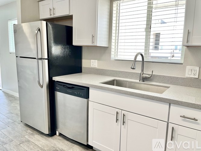 A kitchen with a black fridge and white cabinets.