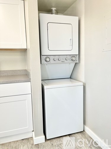 A white dishwasher is in a kitchen next to a white cabinet.