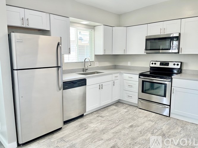 A kitchen with a refrigerator, oven, microwave, and sink.