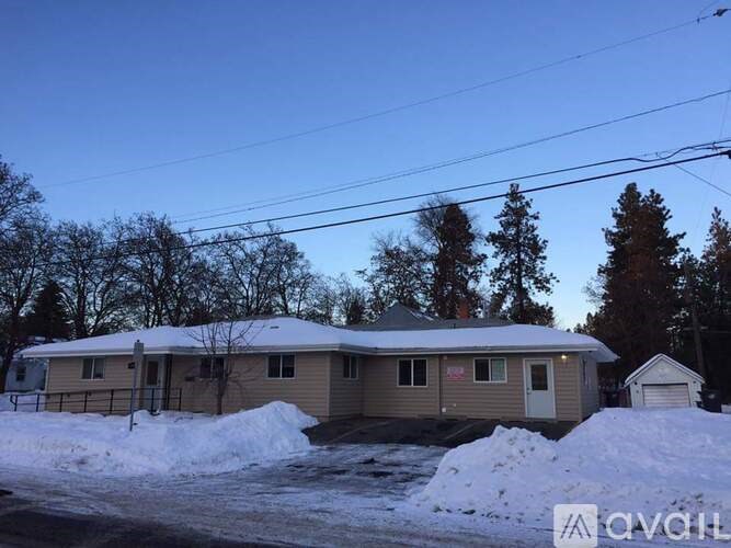 A house with a snow-covered ground in front of it.