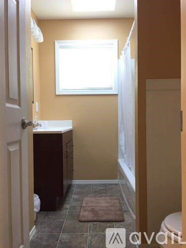 A bathroom with a toilet, sink, and window.