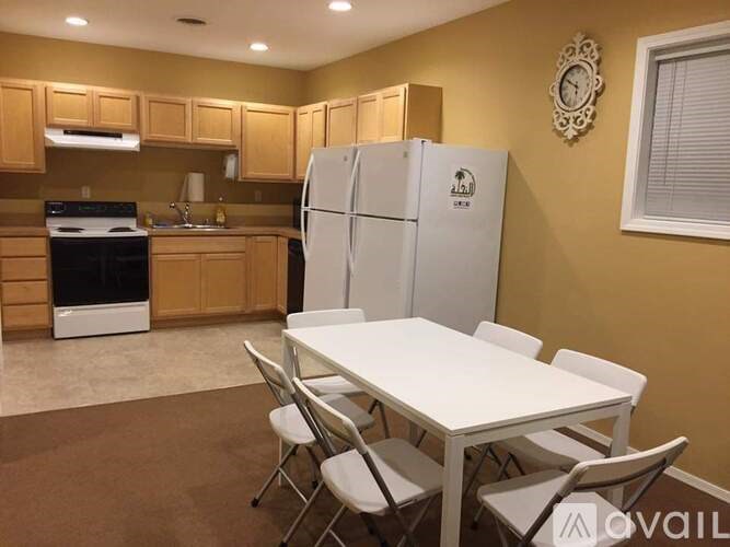 A kitchen with a table and chairs in front of a refrigerator.