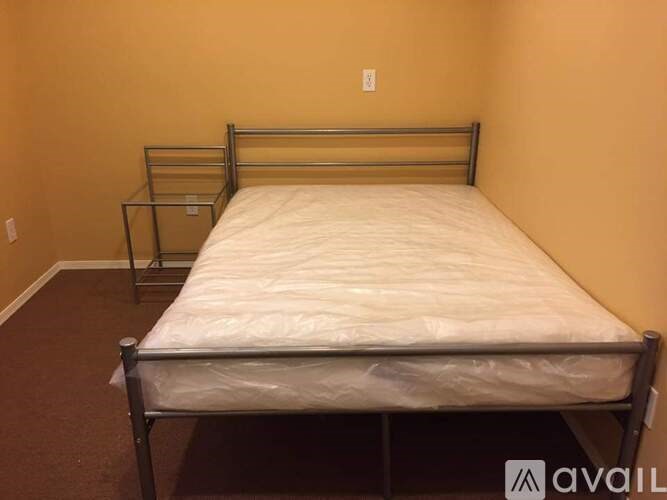 A bed with a white sheet and a metal frame in a room.