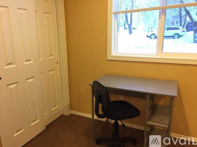 A room with a desk and chair in front of a window.