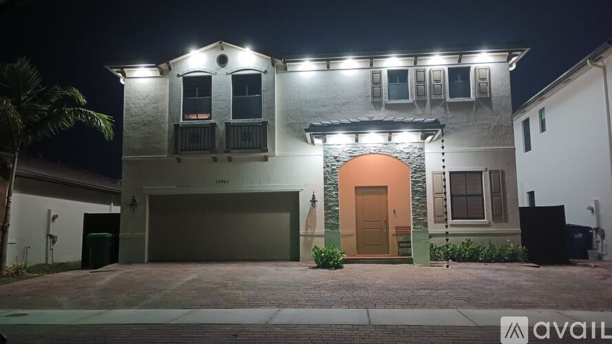 A house with a lit up entrance and garage doors.