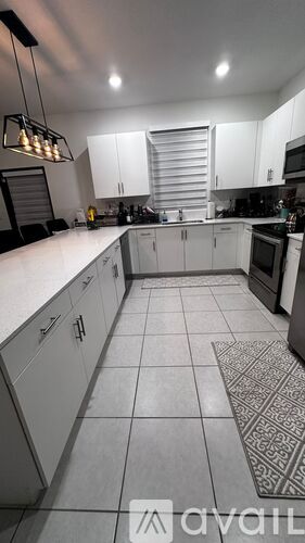 A kitchen with white cabinets and a patterned rug on the floor.