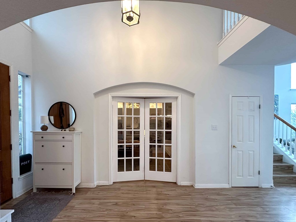 A white room with a wooden floor and a white door with glass panels.