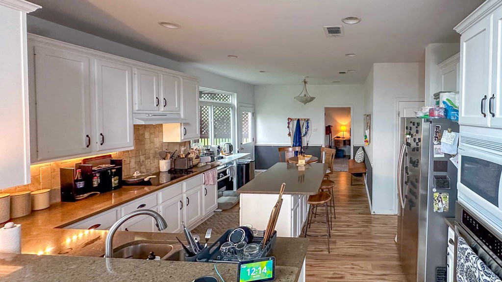 A kitchen with white cabinets and a wooden floor.