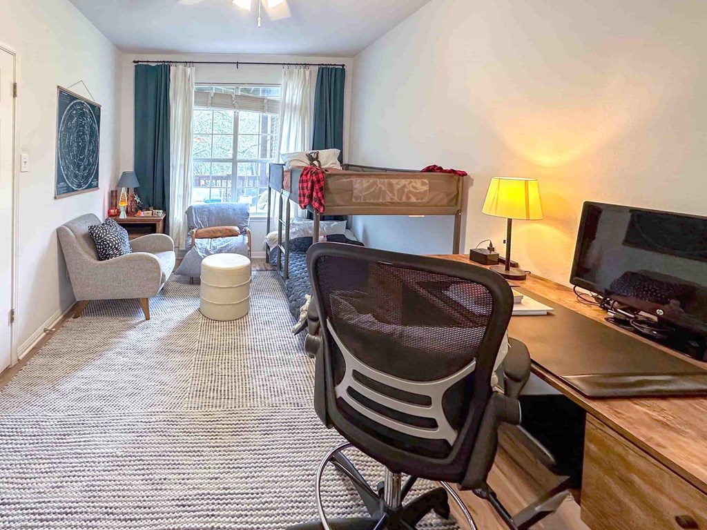 A room with a desk, chair, and a bed.