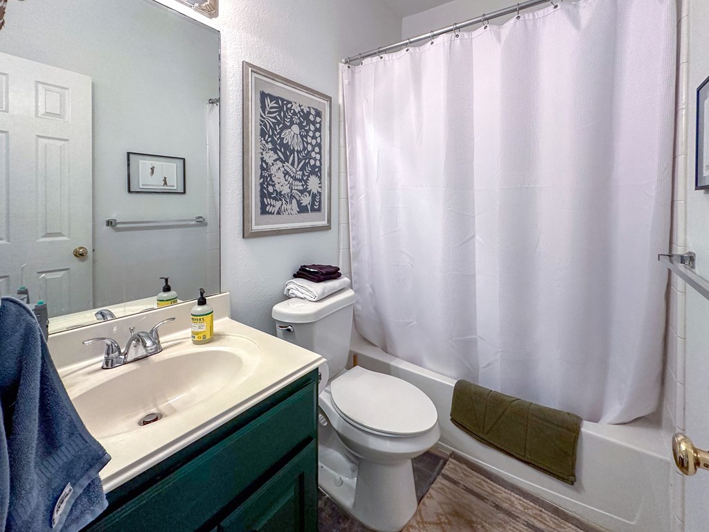 A bathroom with a white toilet, a white sink, and a white shower curtain.